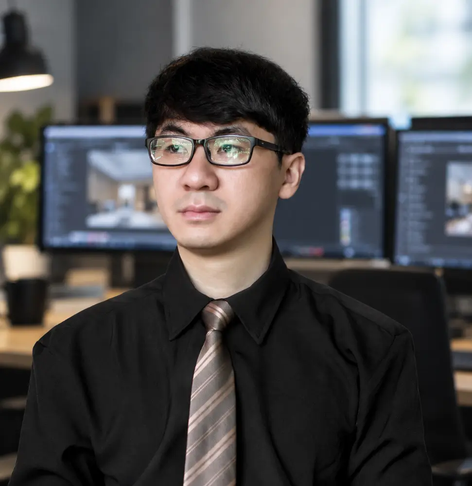 Professional portrait photograph of Tai Nguyen, Chief Technology Officer of Our-Inspiration, wearing glasses, a black shirt, and a tie, posing in an office environment with computer monitors in the background.